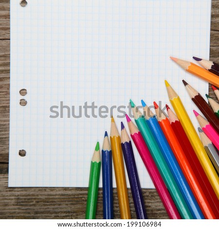 Checkered sheet and pencils on the wooden background