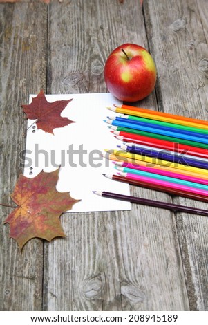 Checkered sheet, maple leaf and pencils on the wooden background