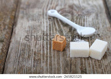 White and brown sugar and white spoon on old brown table .