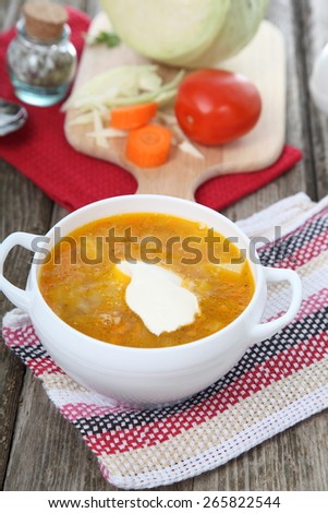 Cabbage soup in a white plate on old wooden table .