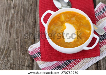 Cabbage soup in a white plate on old wooden table .