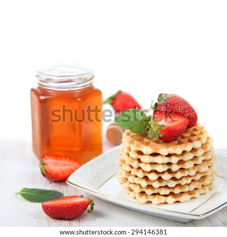 Jar of honey, ripe strawberries and waffles. Delicious summer dessert.