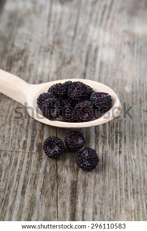 Ripe blackberries in a wooden spoon on the table