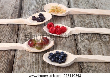 Different ripe berries in a wooden spoons on the table