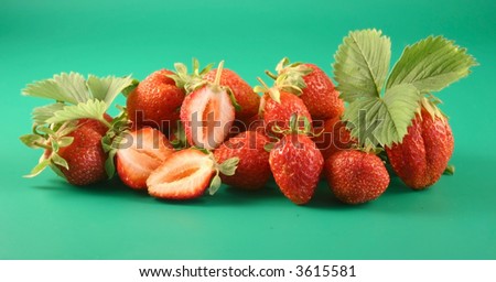 Some strawberries lay on a green background with a leaflet