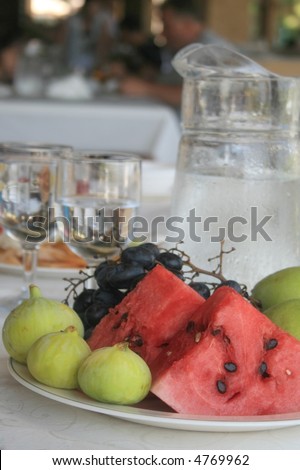 Grapes, a fig and a water-melon on a background of a jug with water