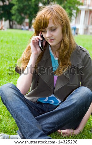 The girl talks by a mobile phone in park.