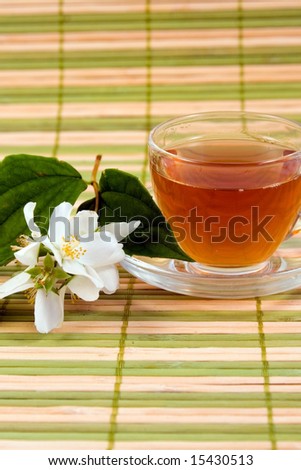 Transparent teacup with tea and flower