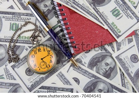 Pocket watch, notebook and pen on a stack of dollars, reflecting time and money