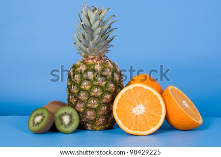 Pineapple, oranges and kiwi on a blue background