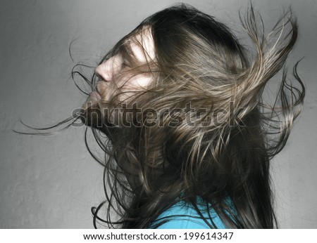 Arty portrait of a fashionable male model with long hair over dark gray background. studio shot