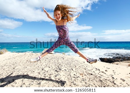 Happy girl full of excitement jumping on a beach. Vacations by the sea