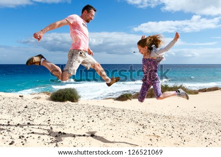 Happy people jumping on a beach. A girl and her father enjoying their vacations