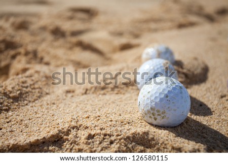 Three golf balls in a sand trap