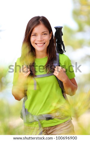Hiker portrait - hiking woman standing smiling happy in forest clearing. Beautiful sporty healthy lifestyle image of young fresh multiracial hiker woman on trek.
