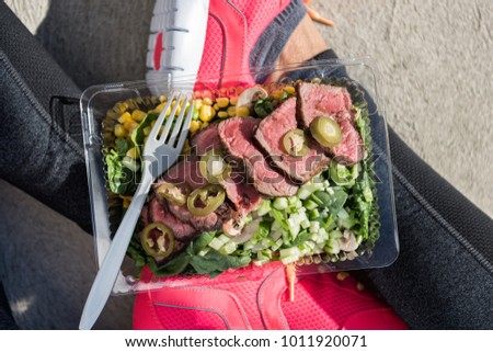 Meal prep fitness lifestyle - Woman taking food selfie top view photo of her prepared ready to go lunch box for healthy paleo diet - Steak salad take-out eating girl at gym.