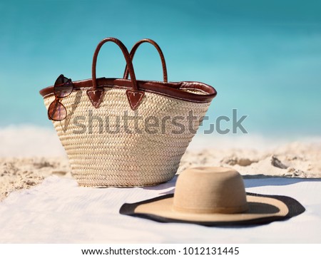 Sun vacation beach winter travel holiday background- Beach bag, fashion hat and sunglasses for Caribbean relaxation. . Copy space on blue ocean. Fashion stylish luxury accessories.