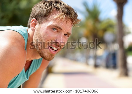 Sweating fitness man tired exausted of running in sun heat dehydrated with sweat dripping from face. Sunstroke athlete jogger jogging outside in city. Active sport lifestyle.