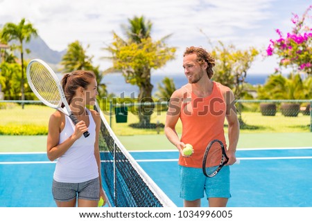 Tennis players friends having fun laughing playing on outdoor court. Couple or mixed double tennis partners outside in summer. Happy young people, woman and man living healthy active sport lifestyle.