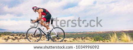 Triathlon biking man cycling on road bike in nature background banner. Cyclist triathlete riding bicycle in ironman competition. Panorama header crop for landscape copy space.