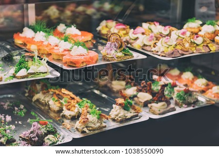 Danish smorrebrod traditional open sandwich at Copenhagen food market store. Many sandwiches on display with seafood and meat, smoked salmon.