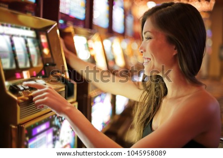 Asian woman gambling in casino playing on slot machines spending money. Gambler addict to spin machine. Asian girl player, nightlife lifestyle. Las Vegas, USA.