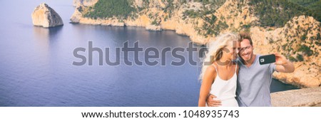 Selfie tourists couple banner panorama young people taking photo with mobile phone on Europe travel destination beach in Mediterranean sea, Mallorca. Caucasian woman and man.