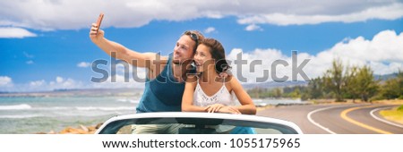 car road trip vacation young people taking selfie photo with phone during summer travel vacation. Tourists couple taking photos on Hawaii in convertible car, with smartphone camera. Banner panorama.