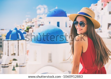 Travel Europe summer holiday girl enjoying Oia, Santorini Greece cruise vacation. Sun getaway Asian woman smiling in hat and sunglasses.