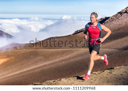 Trail running runner man on endurance run with backpack on volcano mountain. Ultra marathon race athlete on volcanic rocks path in mountains landscape.