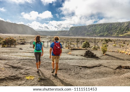 Couple tourists hikers walking on Kilauea Iki crater trail hike in Big Island, Hawaii. USA summer travel vacation destination for outdoor nature adventure, american tourism.