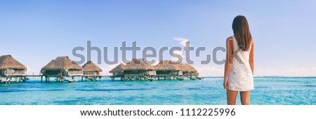 Luxury travel Tahiti vacation tourist woman at overwater bungalows famous resort in French Polynesia. Girl at tropical holiday destination panoramic banner landscape background.