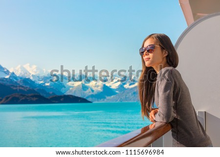 Luxury travel Alaska cruise holiday woman relaxing on balcony looking at view of mountains and nature landscape. Asian girl sunglasses tourist.