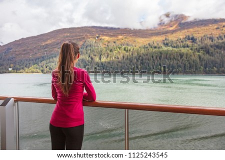 Woman tourist on scenic Alaska cruise in Glacier bay sailing in inside passage. USA vacation travel. Tourist watching autumn foliage passing by, nature outdoors.
