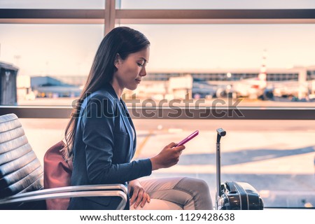 Airport phone travel Asian businesswoman using mobile smartphone in business class lounge waiting for plane flight texting sms message. Technology and travel people VIP lifestyle.