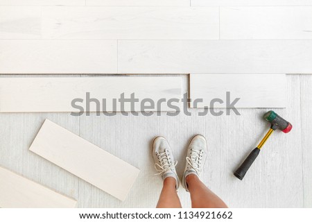 Home improvement floor installation - Worker installing new hardwood flooring at house or condo .Engineered wood floor planks of natural white maple wood. Flooring glued or floating over membrane.