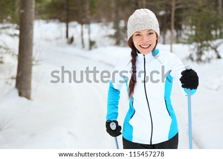 Cross-country skiing woman doing classic nordic cross country skiing in trail tracks in snow covered forest in Quebec, Canada