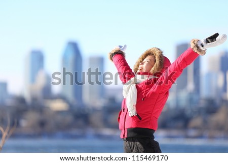City winter woman happy standing excited and elated with arms raised in joy. Beautiful young woman and Montreal City skyline, Quebec, Canada.