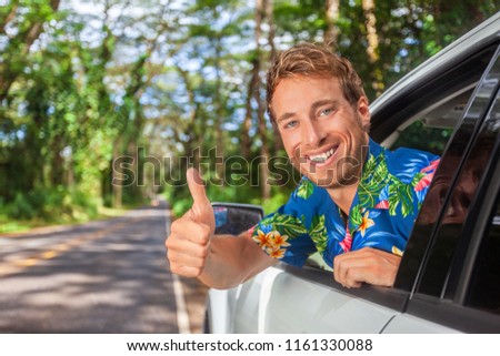 Happy car driver man driving safe on road trip travel doing thumbs up in satisfaction of cars rental. Smiling young male model.