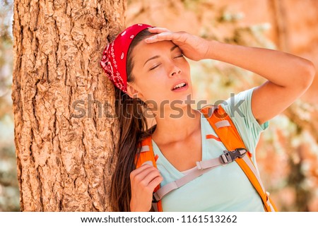 Dehydrated tired hiking woman thirsty feeling exhausted of heat stroke. Girl with headache from hot temperature on outdoor activity hiker lifestyle.