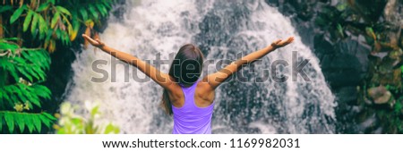 Freedom zen happy girl with open arms meditating yoga at nature waterfall banner panoramic. Hawaii travel woman at Canyon Trail Waipoo Falls in Waimea, Kauai island, USA.