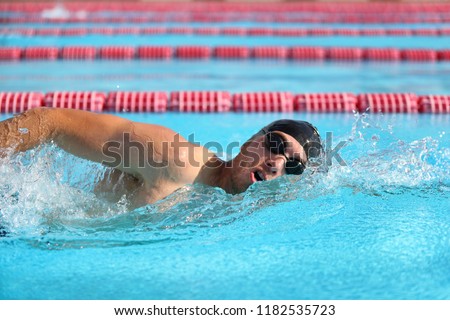 Swimmer man athlete swimming in pool lanes doing a crawl lap. Swim race freestyle.