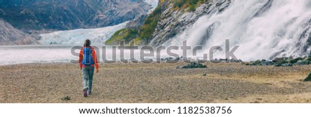 Mendenhall glacier in Juneau, Alaska. Woman tourist hiking with backpack in landscape background, panoramic banner header crop.