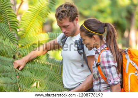 Nature guide biologist naturalist botanist teacher teaching to student about plants and biology. Interpretive walk in rain forest, hiking people studying with backpacks.