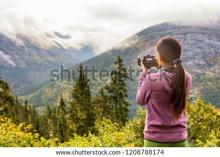 Outdoor travel lifestyle woman photographer shooting video camera at Alaska background. USA vacation holiday in Autumn.