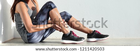 Running sport injury leg pain - runner woman runner hurting holding painful sprained ankle muscle. Female athlete with joint or muscle soreness and problem feeling ache banner panorama.