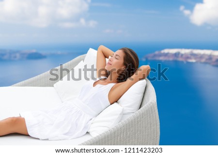 Luxury home lifestyle woman relaxing on comfortable outdoor sofa daybed chair sleeping sun tanning breathing fresh air on ocean background. Asian girl in comfort.