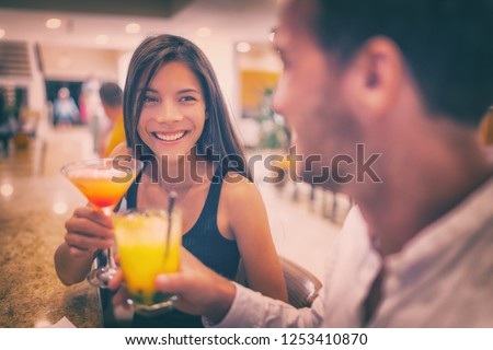 Bar drinking cocktails young couple in love dating talking with drinks at restaurant at night. People at restaurant with alcoholic cocktail beverage.