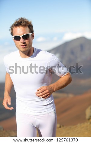 Running man. Male runner jogging outside in mountain landscape doing trail running in training for marathon race. Fit male fitness athlete in outdoor workout wearing sunglasses and compression clothes
