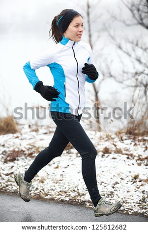 Fit slender young woman taking her daily exercise out jogging in a snowy landscape in winter